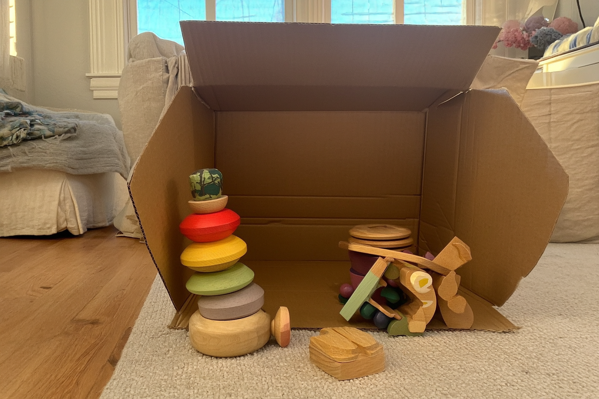 A few curated wooden toys next to an open, empty delivery box