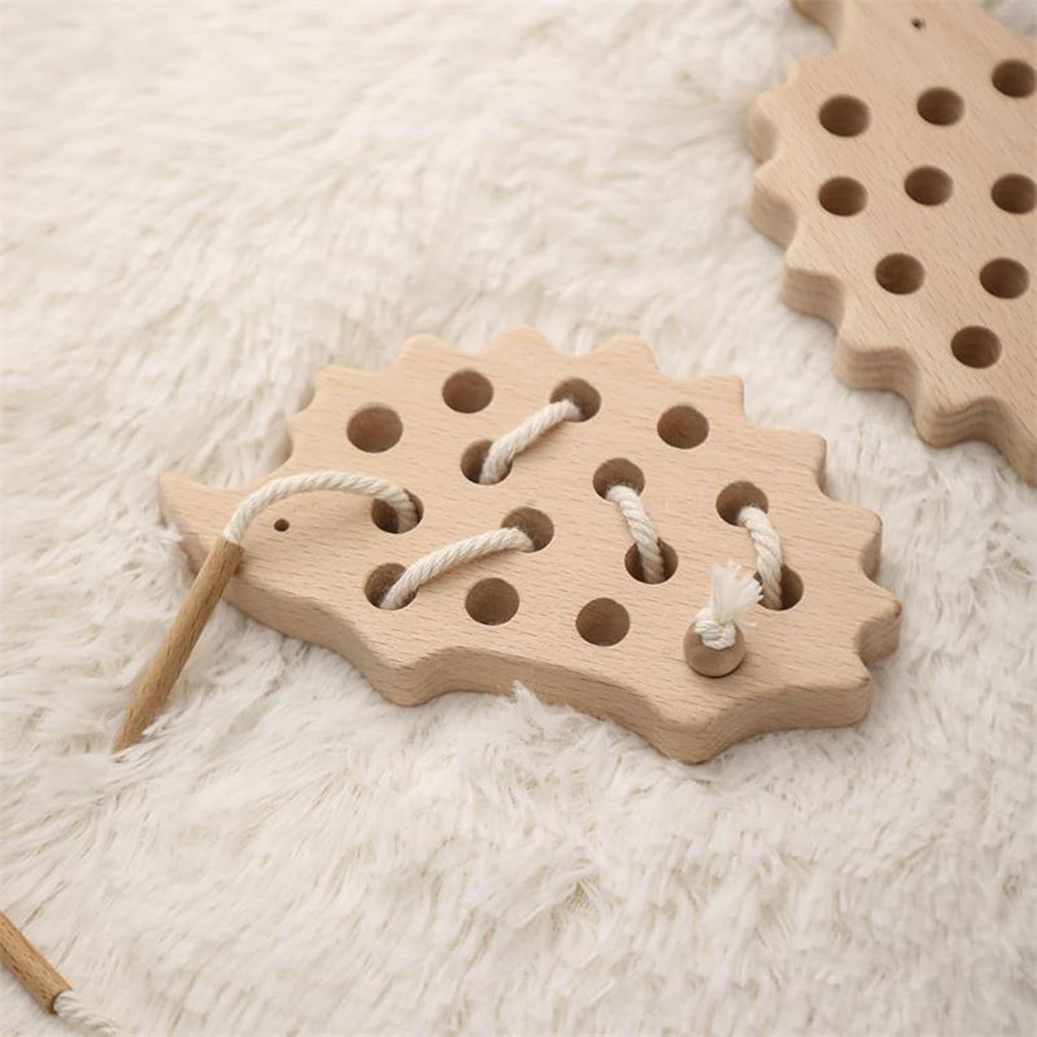 Two wooden hedgehog threading toys resting on a soft cream rug
