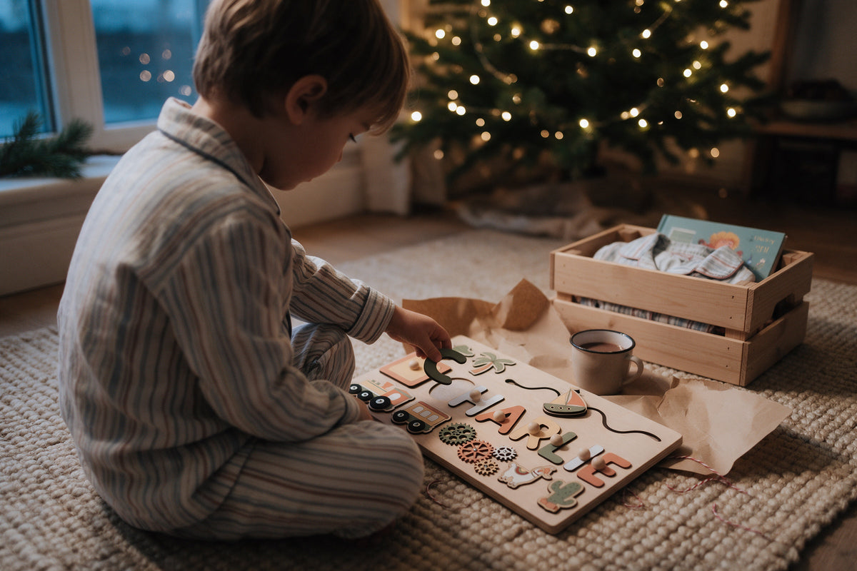 Toddler in pyjamas opening a personalised wooden name puzzle on Christmas Eve